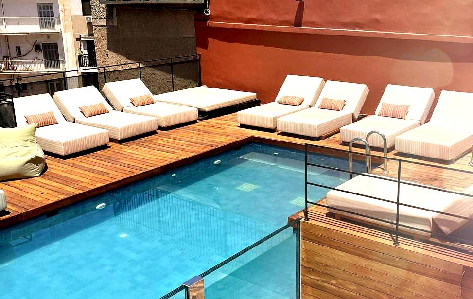 rooftop pool with wooden deck and lounge beds