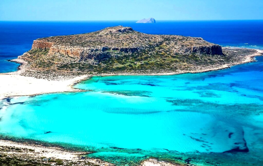 Balos Lagoon is a breathtaking site with turquoise waters and white sand, accessible by boat or hiking