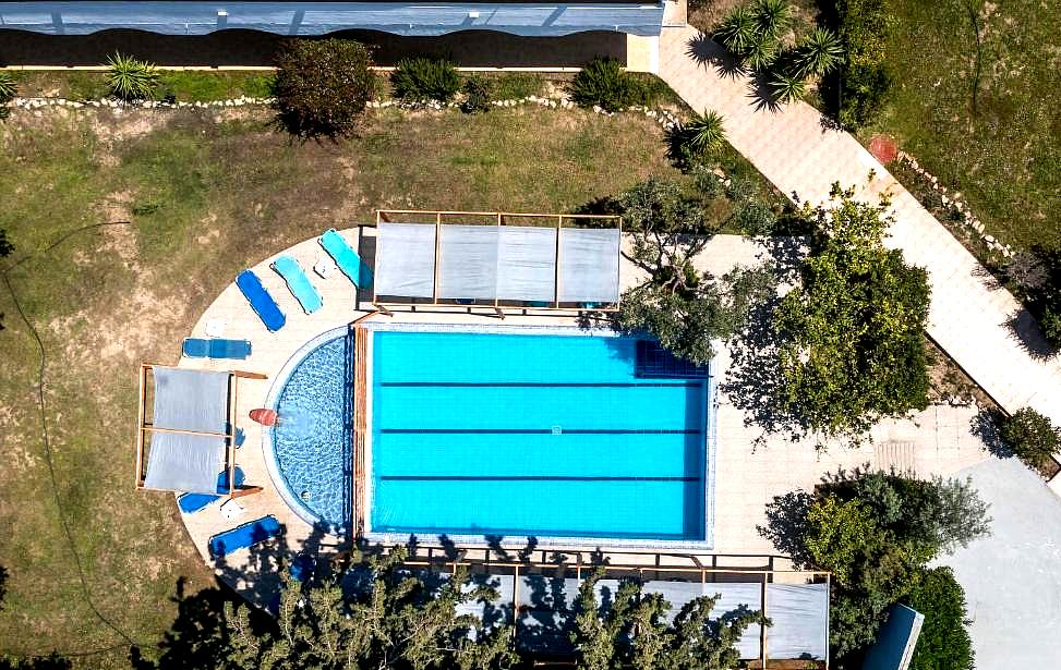 aerial view of outdoor swimming pool with sunbeds and trees