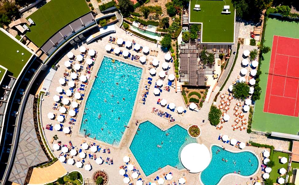 aerial view of pool area with tennis court and sun loungers