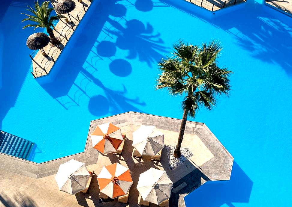 aerial view of pool area with umbrellas and palm trees