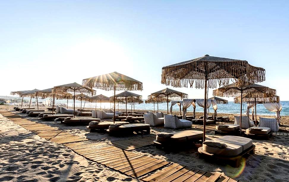 beachfront sun loungers under umbrella canopies on wooden decking