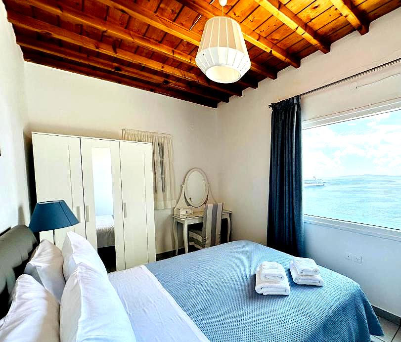 bright bedroom with sea view and wooden ceiling