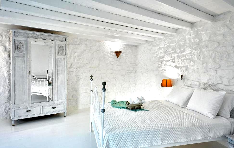 bright bedroom with white stone walls and antique wardrobe