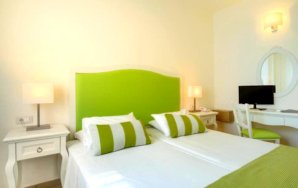 bright hotel room with green accents and cozy decor