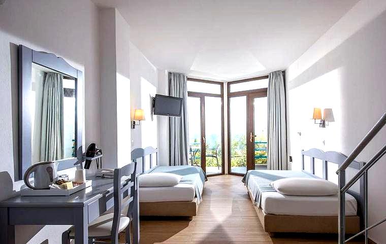 bright room with two beds and large windows facing the sea