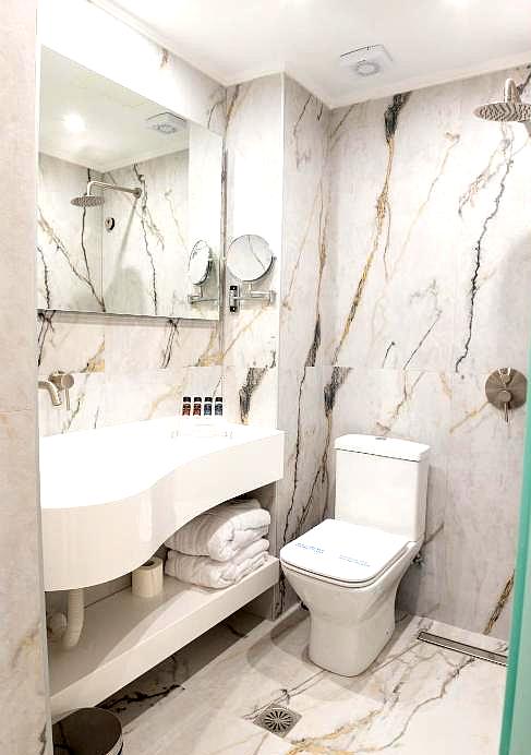 compact marble bathroom with modern fixtures and walk in shower