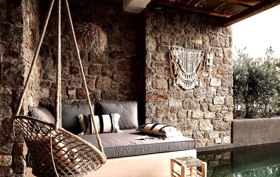 cozy outdoor lounge with hanging chair and stone walls