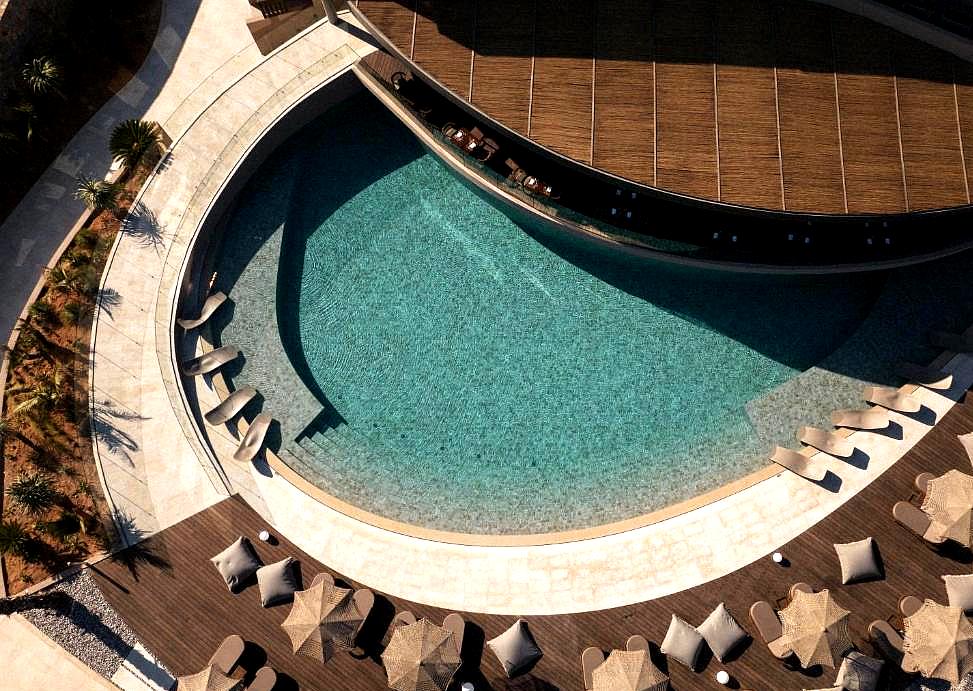 curved swimming pool with poolside loungers and wooden decking