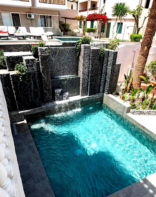 elegant private pool with waterfall feature and lush garden