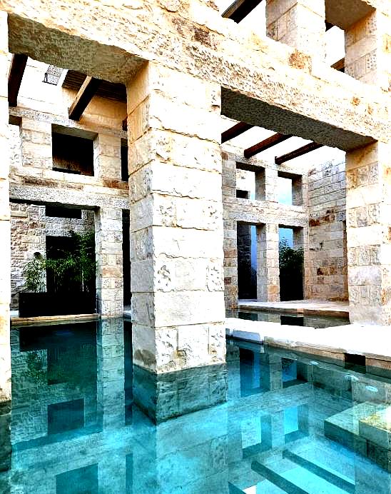 indoor pool area surrounded by stone pillars and arched ceilings