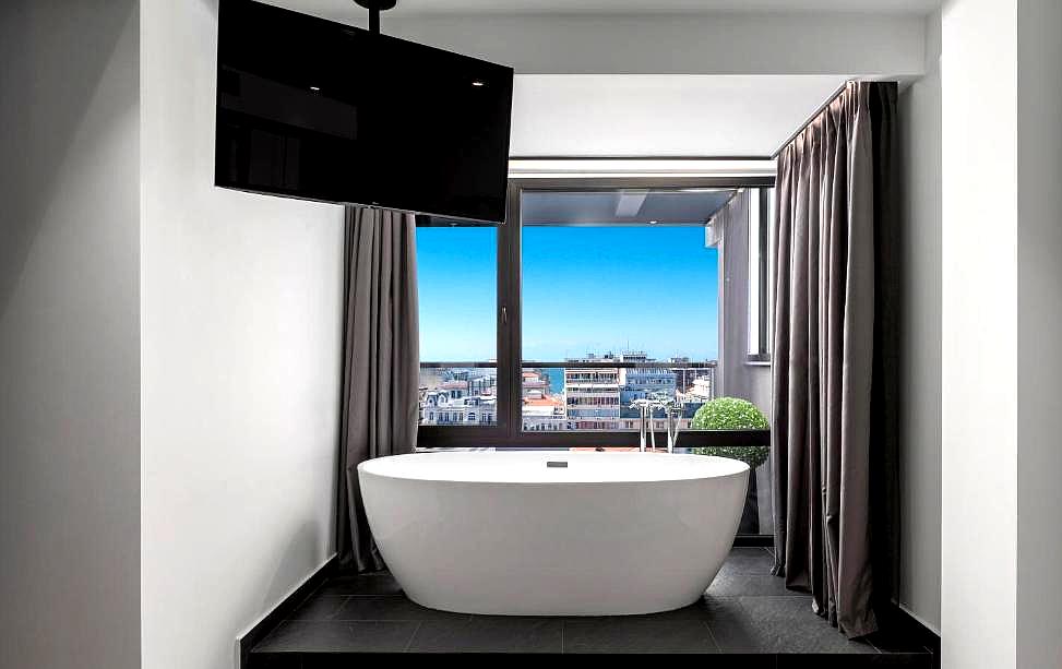 luxurious bathtub with city view and mounted tv