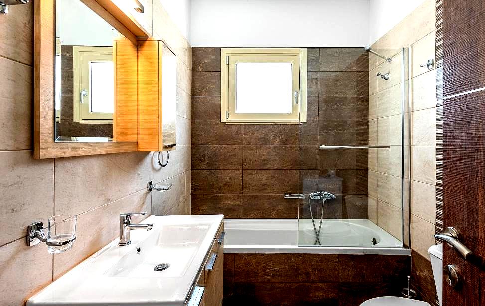 modern bathroom with bathtub wooden cabinets and tiled walls