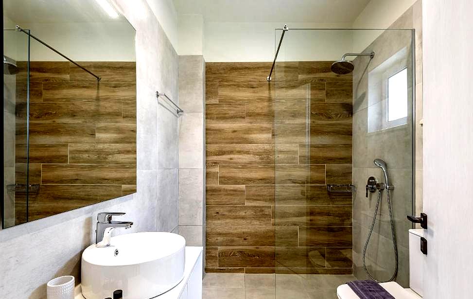 modern bathroom with wooden tiled shower glass divider and white vanity