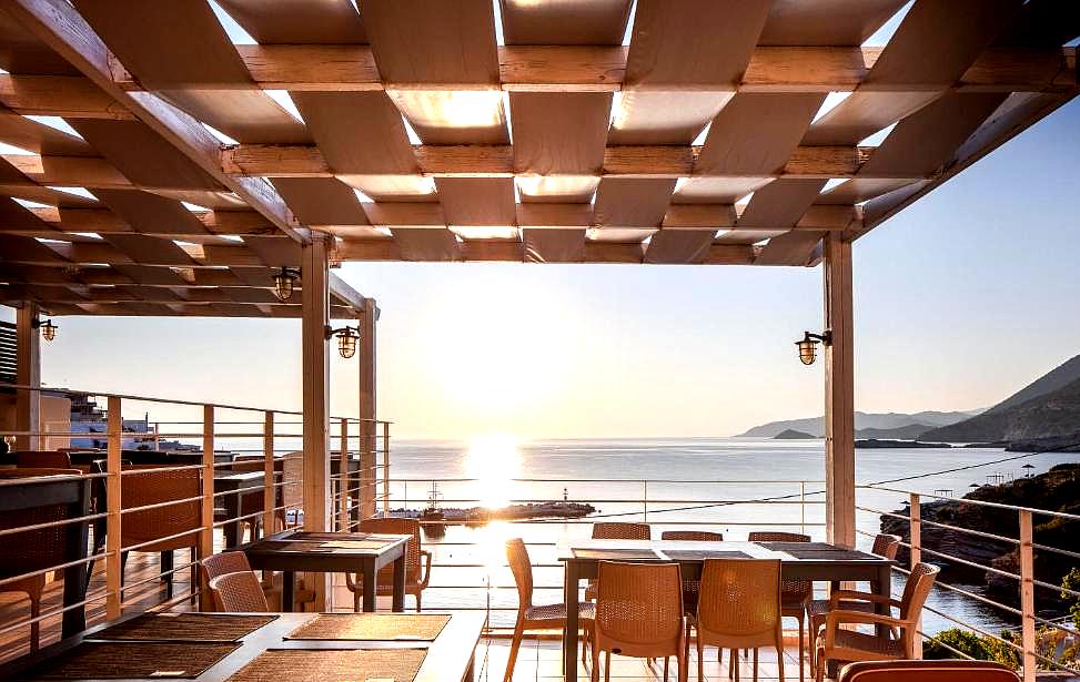 outdoor dining area with wooden pergola and sea view at sunset