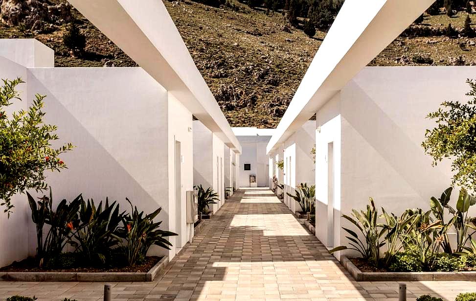 outdoor hallway with white walls and potted plants leading to rooms