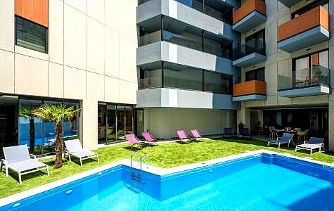 outdoor pool area with lounge chairs and modern building backdrop