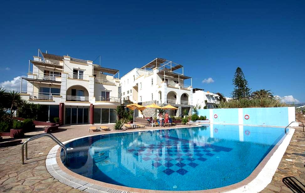 outdoor swimming pool with sun loungers and apartment style buildings