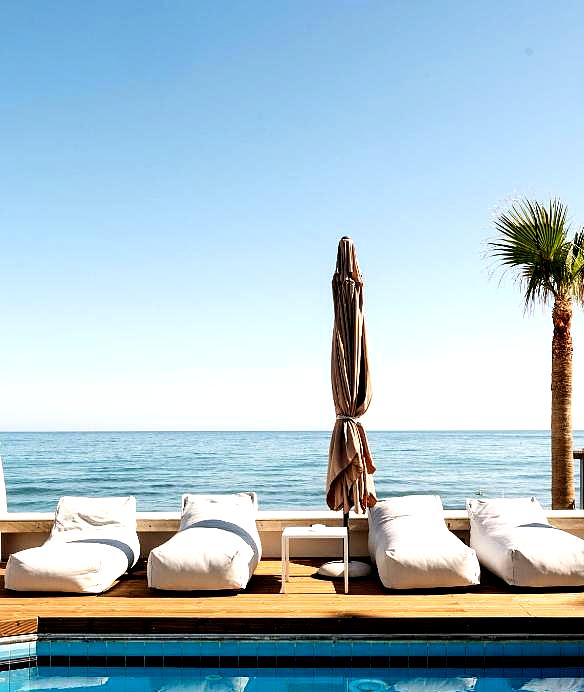 poolside lounge area with sea view and palm trees