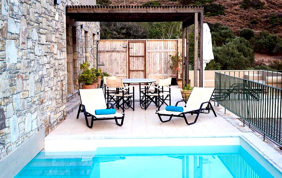 private patio with sun loungers and stone walls by the pool