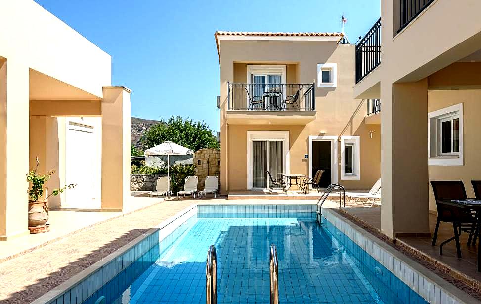 private swimming pool between tan buildings with balconies and lounging area