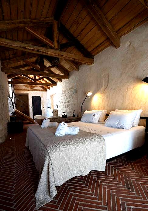 rustic hotel suite with exposed wooden beams and stone walls