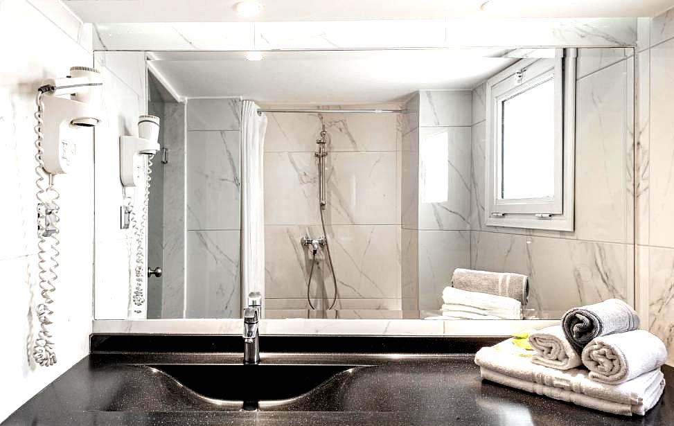 sleek marble bathroom with large mirror and walk in shower