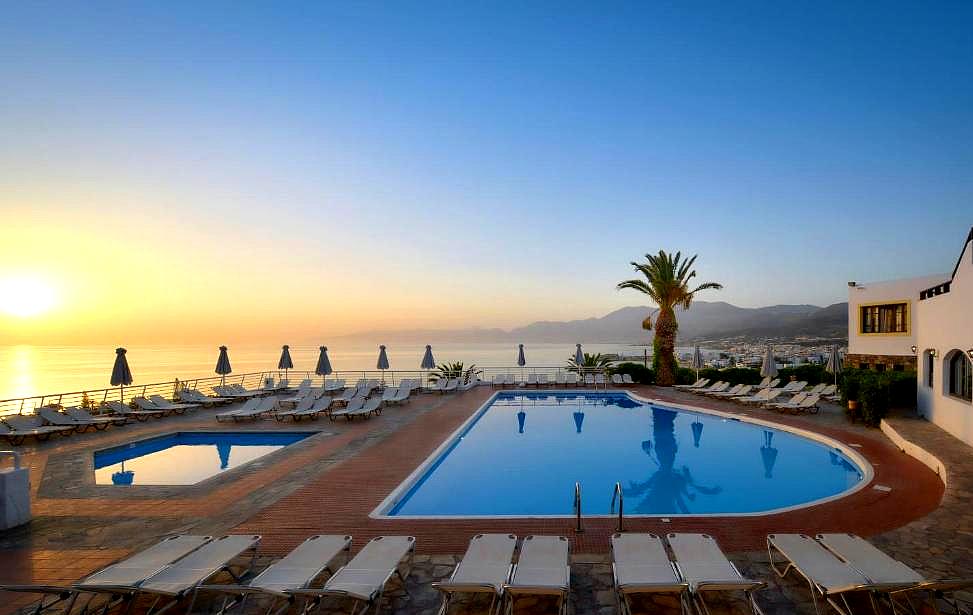 stunning pool area with sun loungers and sea view at sunset