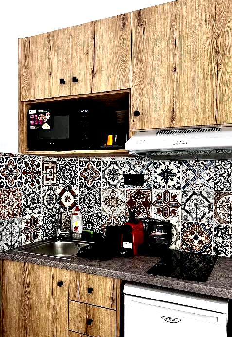 stylish kitchenette with wooden cabinets and colorful tile backsplash