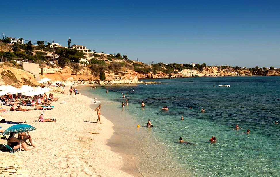 sunny beach with clear water and sunbathers