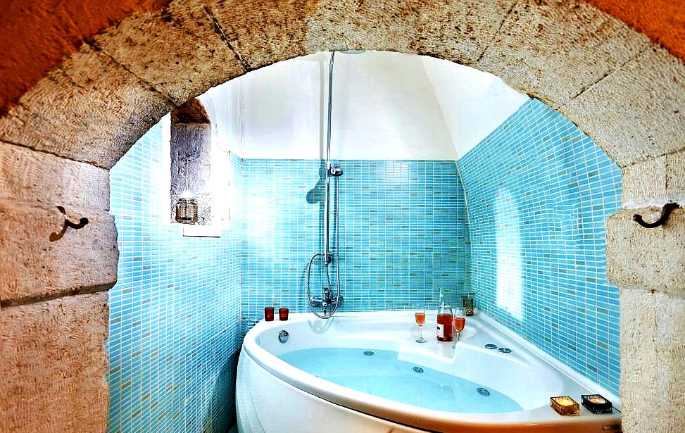 unique bathroom with arched stone wall and modern jacuzzi