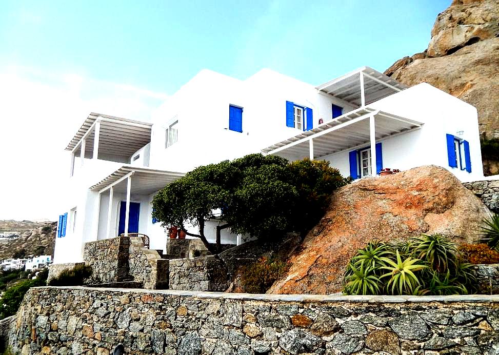 white bungalow with blue shutters and rock garden