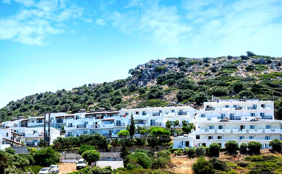 white hotel buildings nestled on green hillside under blue sky